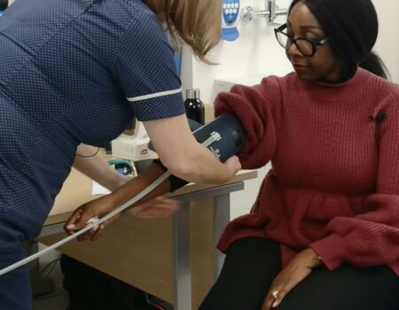 Patient having blood pressure taken by member of staff