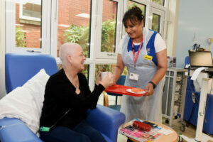 A volunteer giving tea to a patient