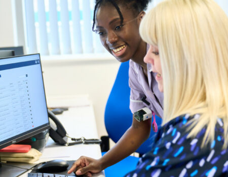 Healthcare support worker on a computer with ward clerk