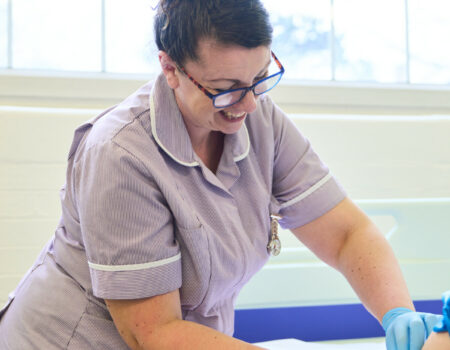 Healthcare support working placing a dressing on patient arm