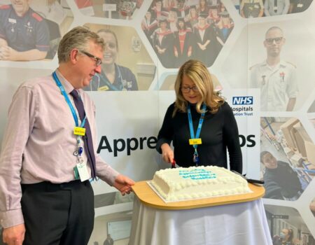 Liz Lees, Chief Nurse, cutting a cake at national apprenticeship week celebration with David Carter, Chief Executive